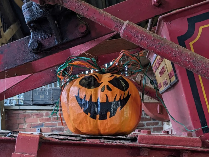 Pumpkin with a drawn on face, sat on machinery
